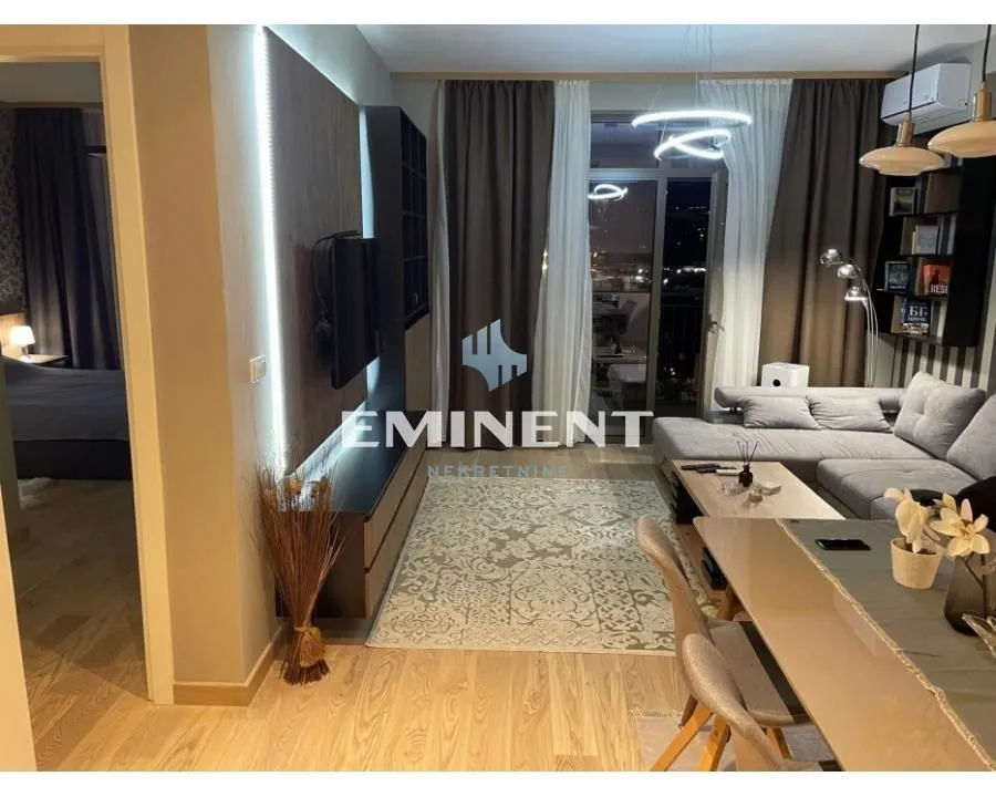 Modern and bright living room with a sofa, TV, and dining area.