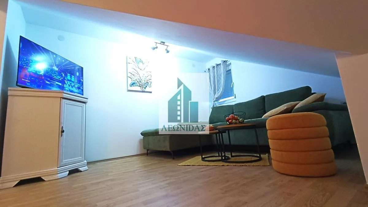 Living room with a green corner sofa, television, and low sloping ceiling.
