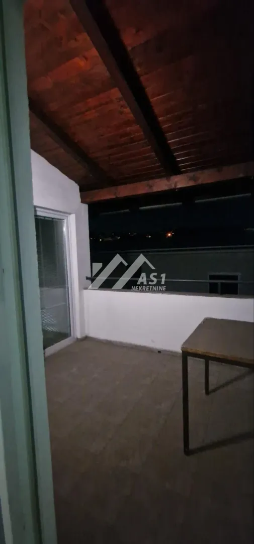 Natkrivena terasa sa drvenom konstrukcijom i pogledom noću.