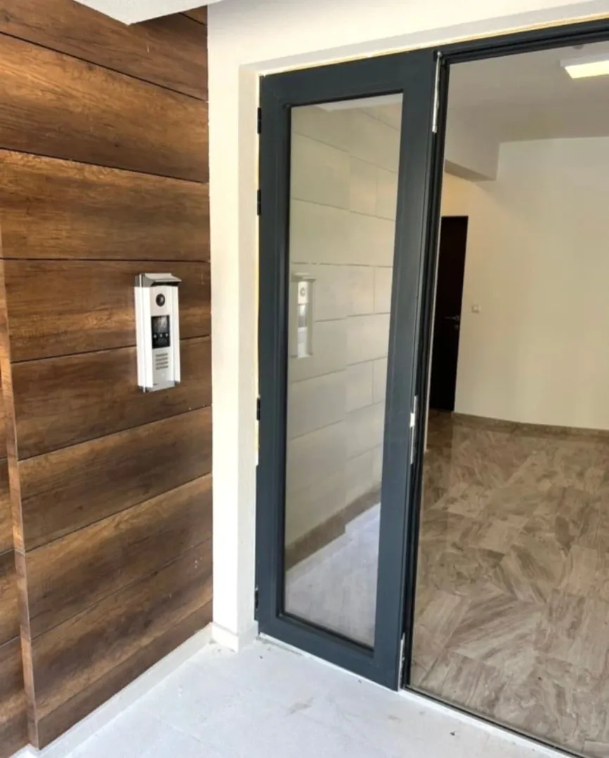 Building entrance door with intercom and wooden wall cladding.