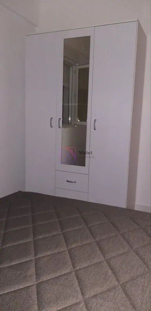 Bedroom with a large white wardrobe with a mirror and a double bed.