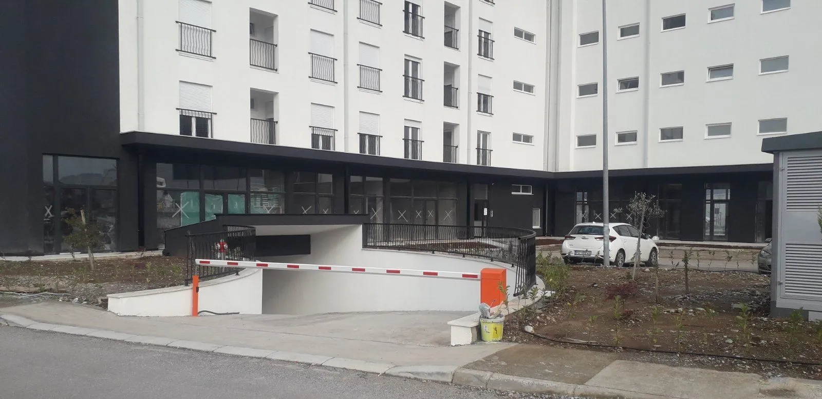 Eksterijer nove stambene zgrade sa prilazom podzemnoj garaži.