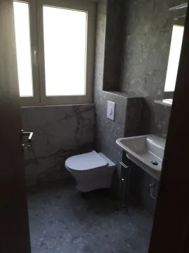 Manje kupatilo obloženo sivim pločicama sa ugradnom šoljom i umivaonikom. - image 8