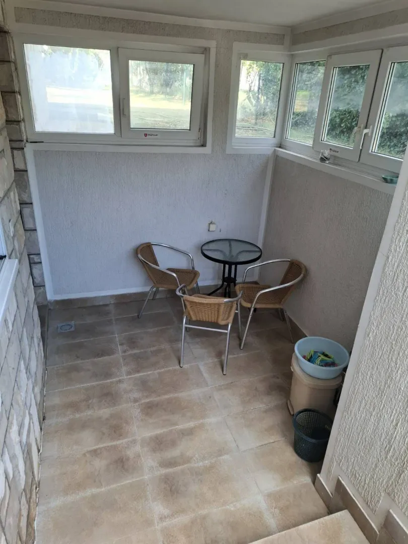 Enclosed terrace with seating furniture and tiled flooring.