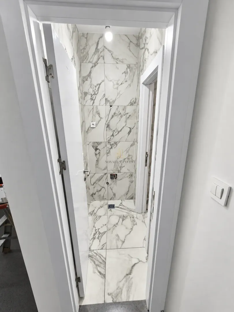A view of a bathroom under construction lined with marble tiles.