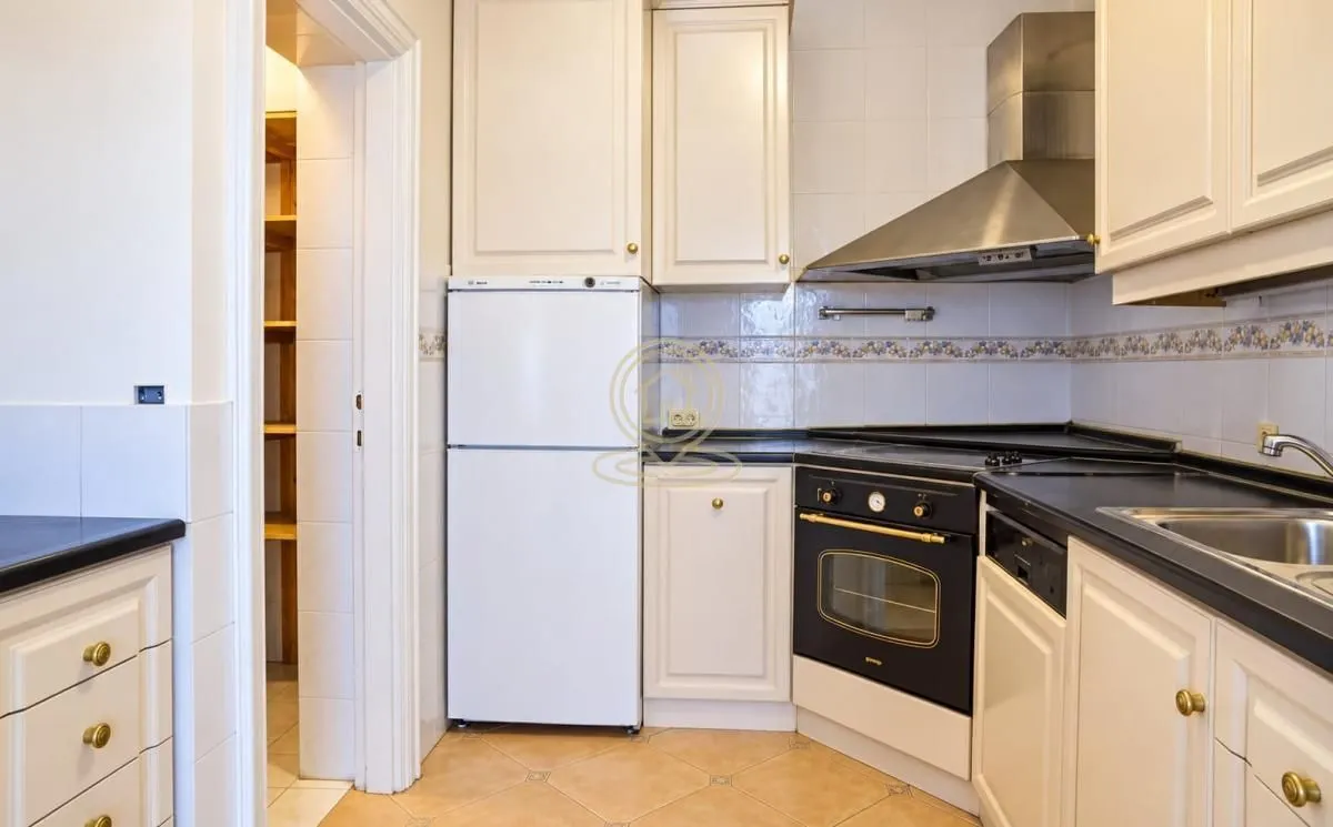 Small kitchen with white cabinets, refrigerator, and stove.