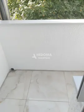 Pogled na manji popločani balkon sa belom ogradom i zelenilom u pozadini. - image 6