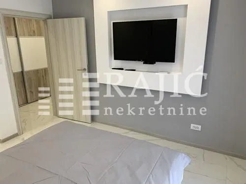 Modern bedroom with a double bed, wall-mounted TV, and built-in wardrobe.