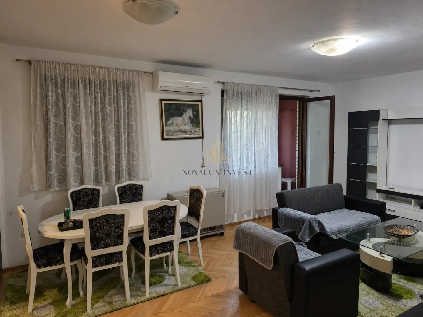 Living room with a dining area, sofa set, and parquet flooring.