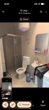 Bathroom equipped with a shower cabin, toilet, sink, and water heater. - image 4