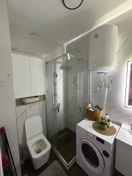 Modern bathroom with a shower cabin, toilet, washbasin, and washing machine. - image 9