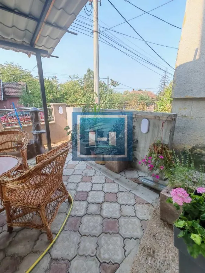 Natkrivena terasa sa garniturom za sedenje i ukrasnim biljem.