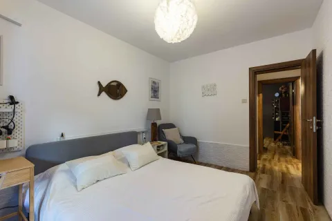 Namještena spavaća soba sa bračnim krevetom, foteljom i otvorenim vratima prema hodniku. - image 14