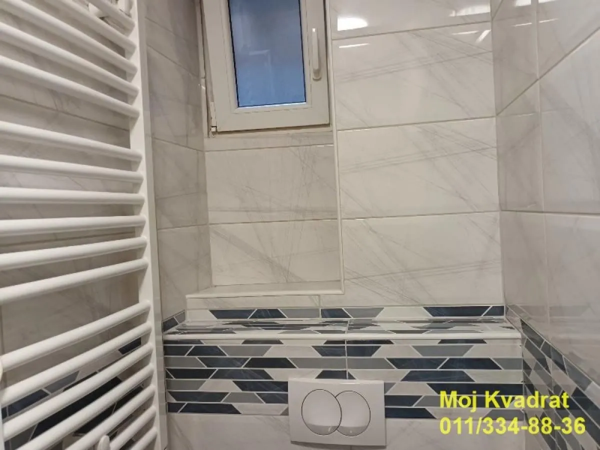 View of the bathroom with white tiles and a built-in radiator.