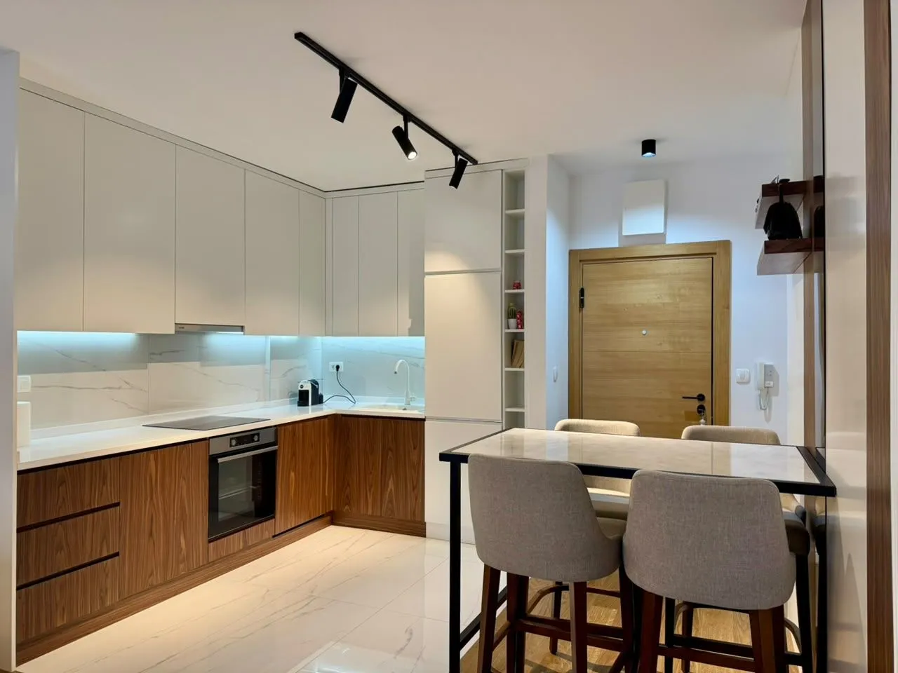 Modern kitchen with white and wooden elements and a dining table.