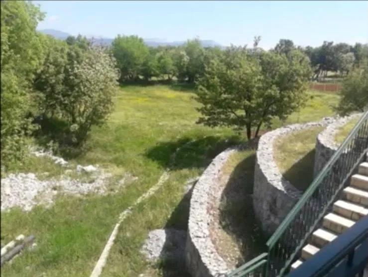 View from the terrace towards a landscaped yard with stone walls and greenery.