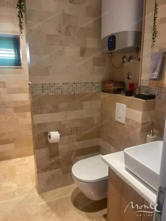 Kupatilo obloženo keramičkim pločicama sa toaletom, umivaonikom i bojlerom.