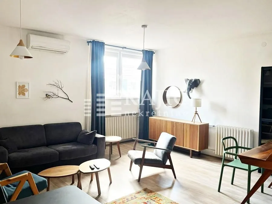 Bright living room furnished with a sofa, armchair, and dining table.