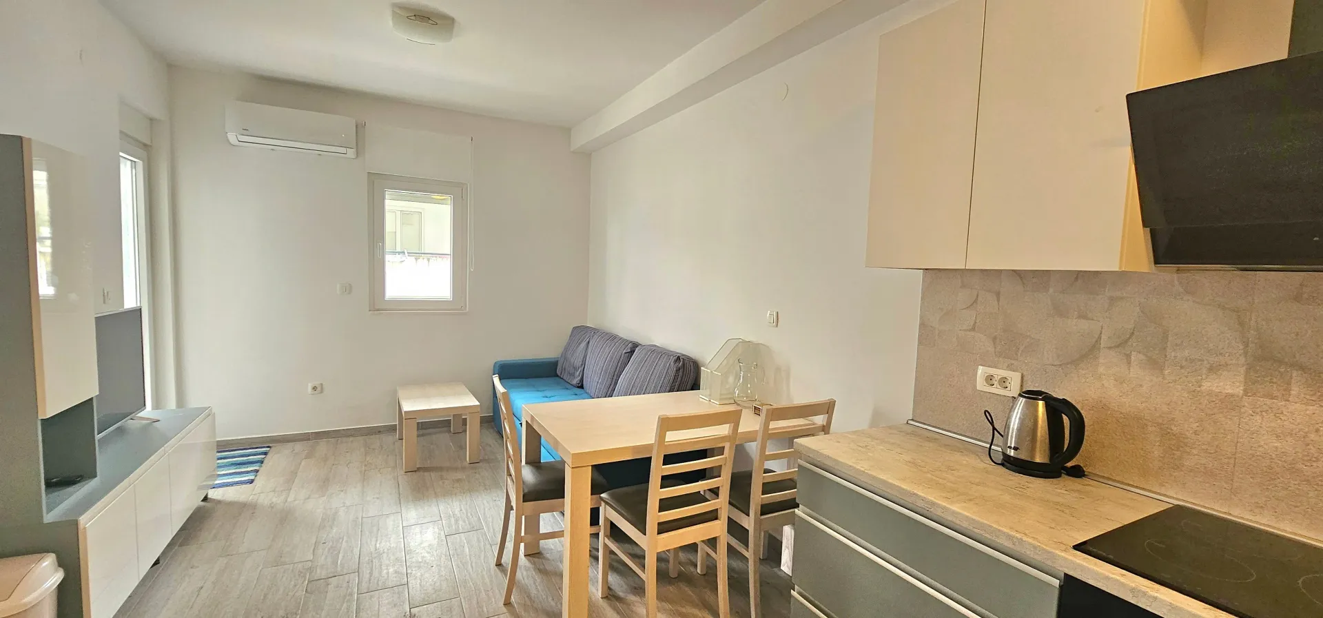 Living room with dining area and kitchen in light tones.