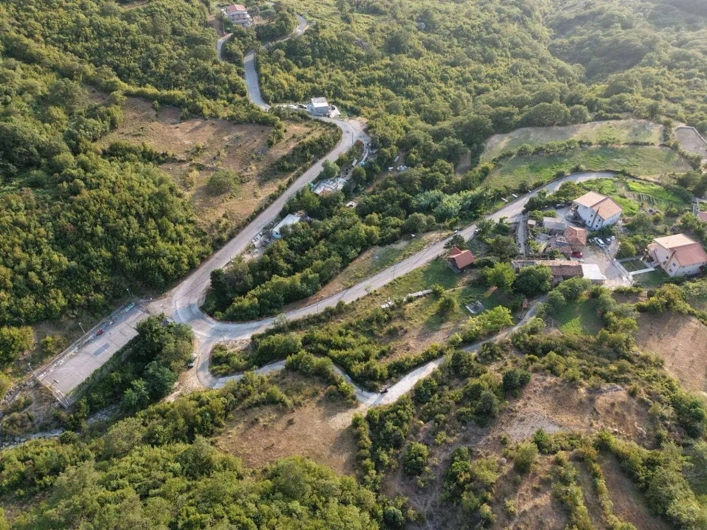 Pogled iz vazduha na prirodu, kuće i put.