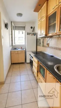 Dugačka kuhinja sa drvenim elementima, frižiderom i prozorom na kraju prostorije. - image 4