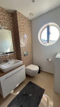 Bathroom equipped with a washbasin, toilet, and round window. - image 3