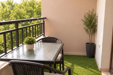 Furnished balcony with a table, chairs, artificial grass, and decorative plants. - image 7