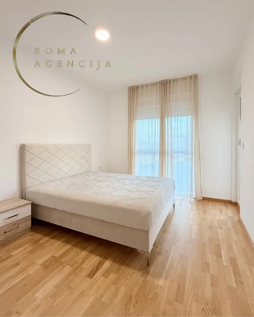 Bright bedroom with a double bed and wooden flooring.