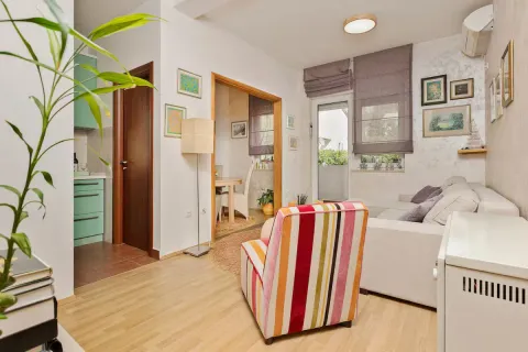 Living room with sofa and colorful armchair, looking toward the dining area and kitchen. - image 6