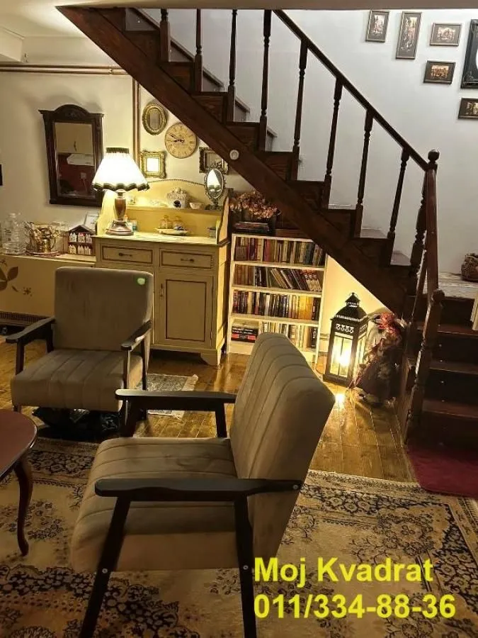 Dnevna soba sa drvenim stepeništem i foteljama.