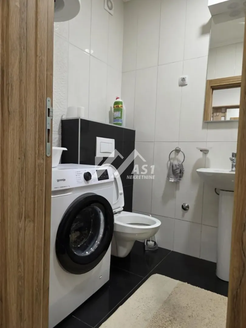 Manje kupatilo sa tuš kabinom, umivaonikom i veš mašinom.