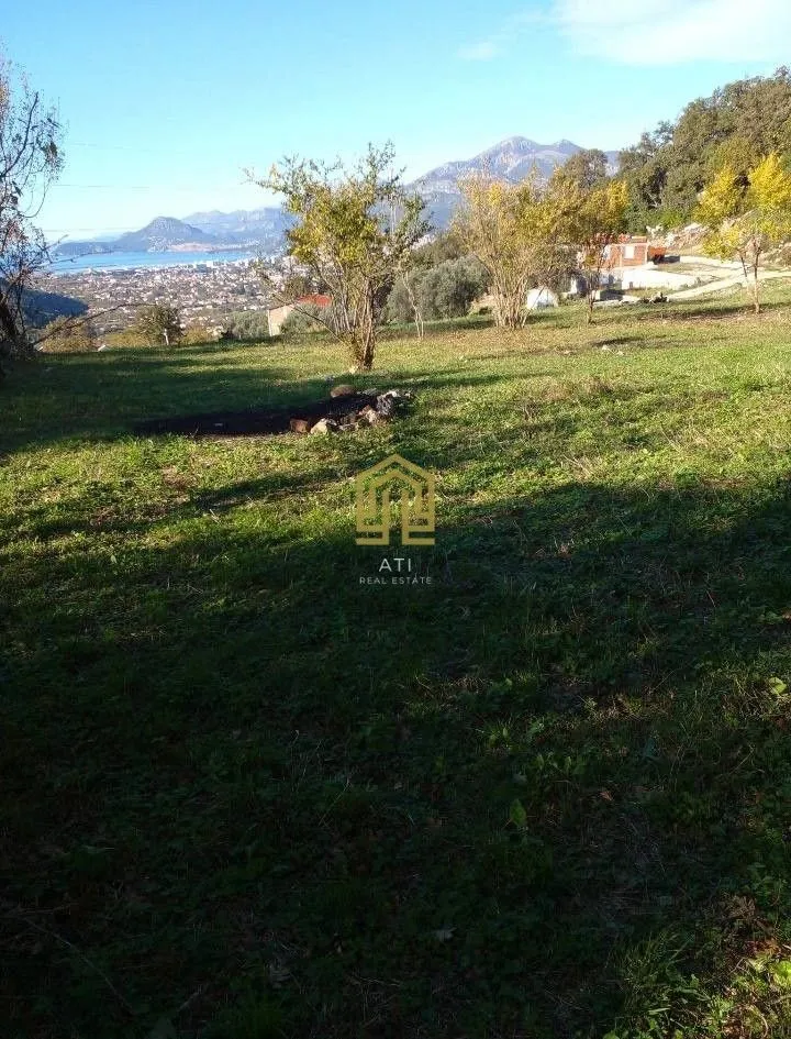 Zeleni plac sa pogledom na grad i more u daljini.