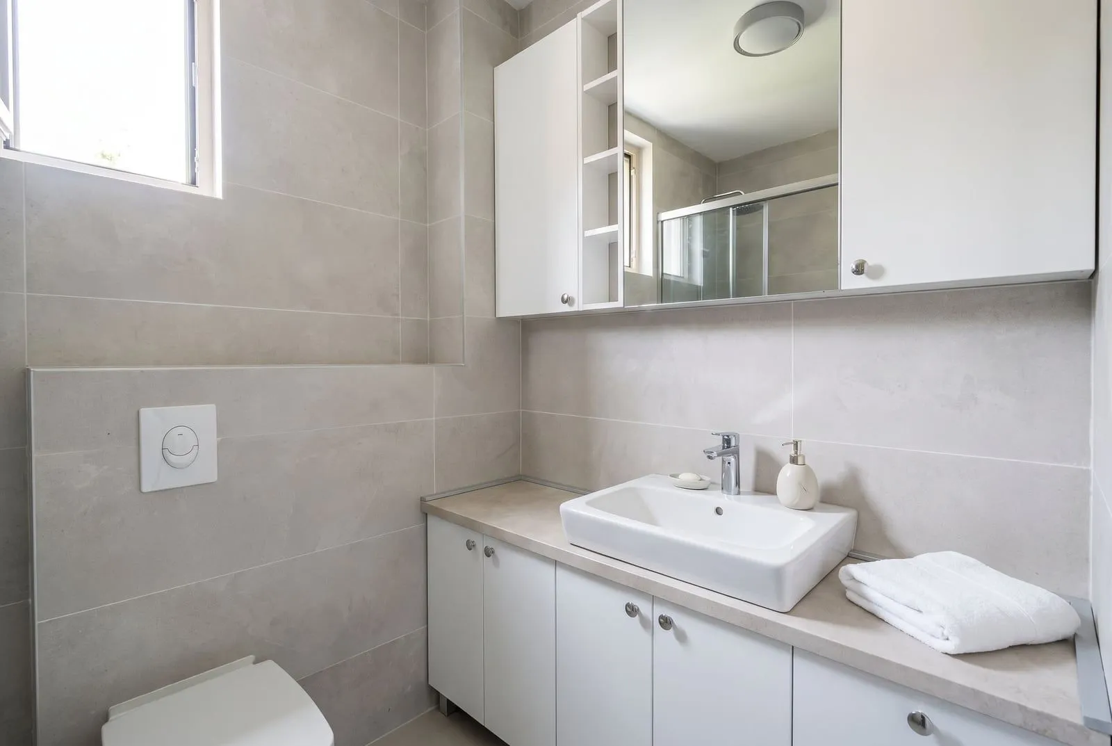 Modern bathroom with a sink, white cabinets and a mirror.