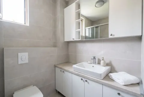 Modern bathroom with a sink, white cabinets and a mirror. - image 9