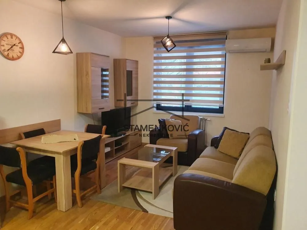 Living room with sofa, TV unit, and dining table.
