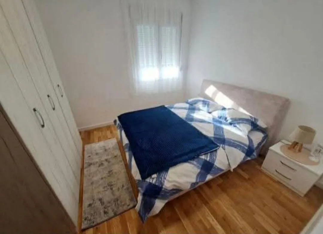Namještena spavaća soba sa bračnim krevetom, plakarom i noćnim stočićem.