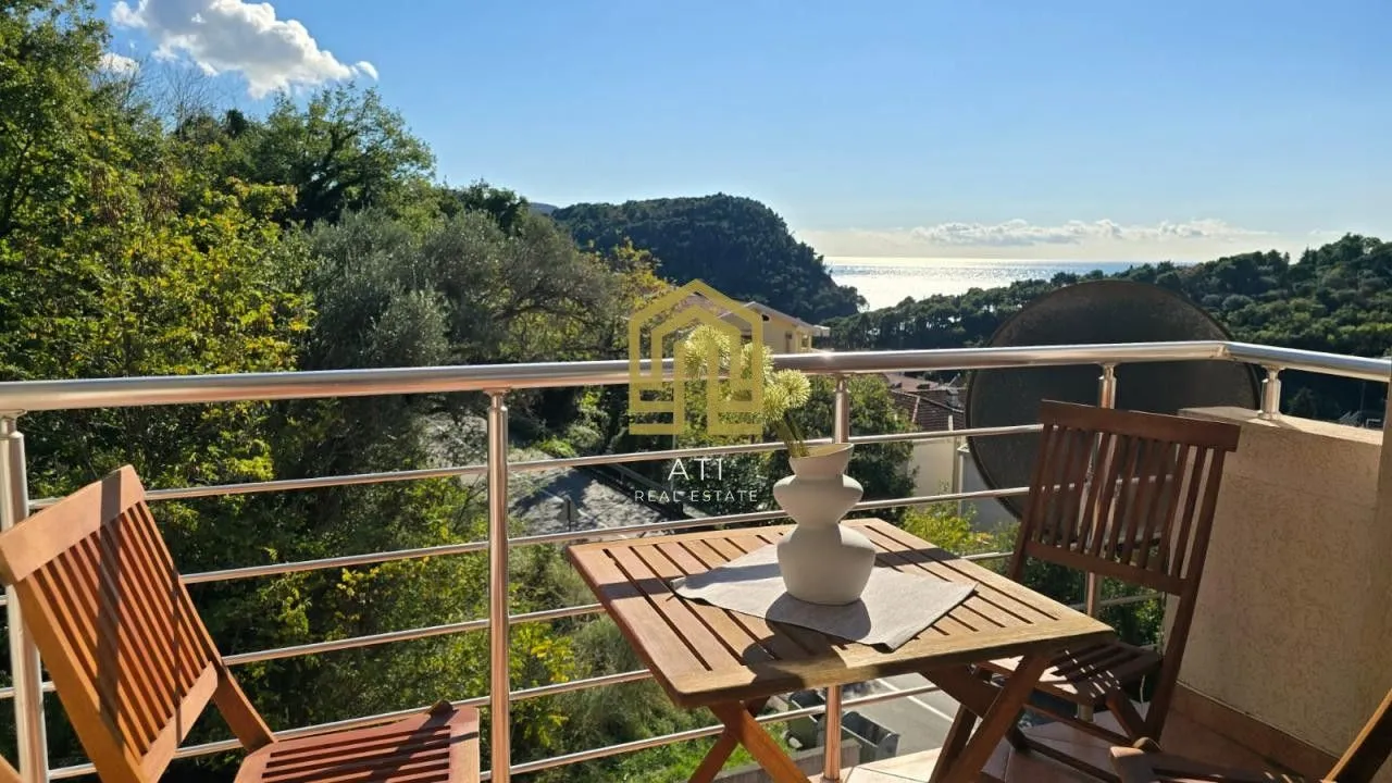 Namješten balkon sa drvenim stolom, stolicama i pogledom na more i prirodu.