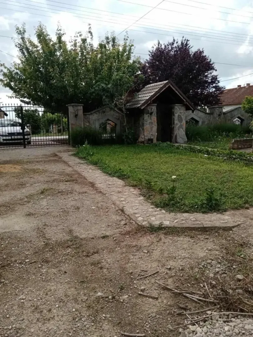 Dvorište sa kapijom, travnjakom i kamenim zidom.