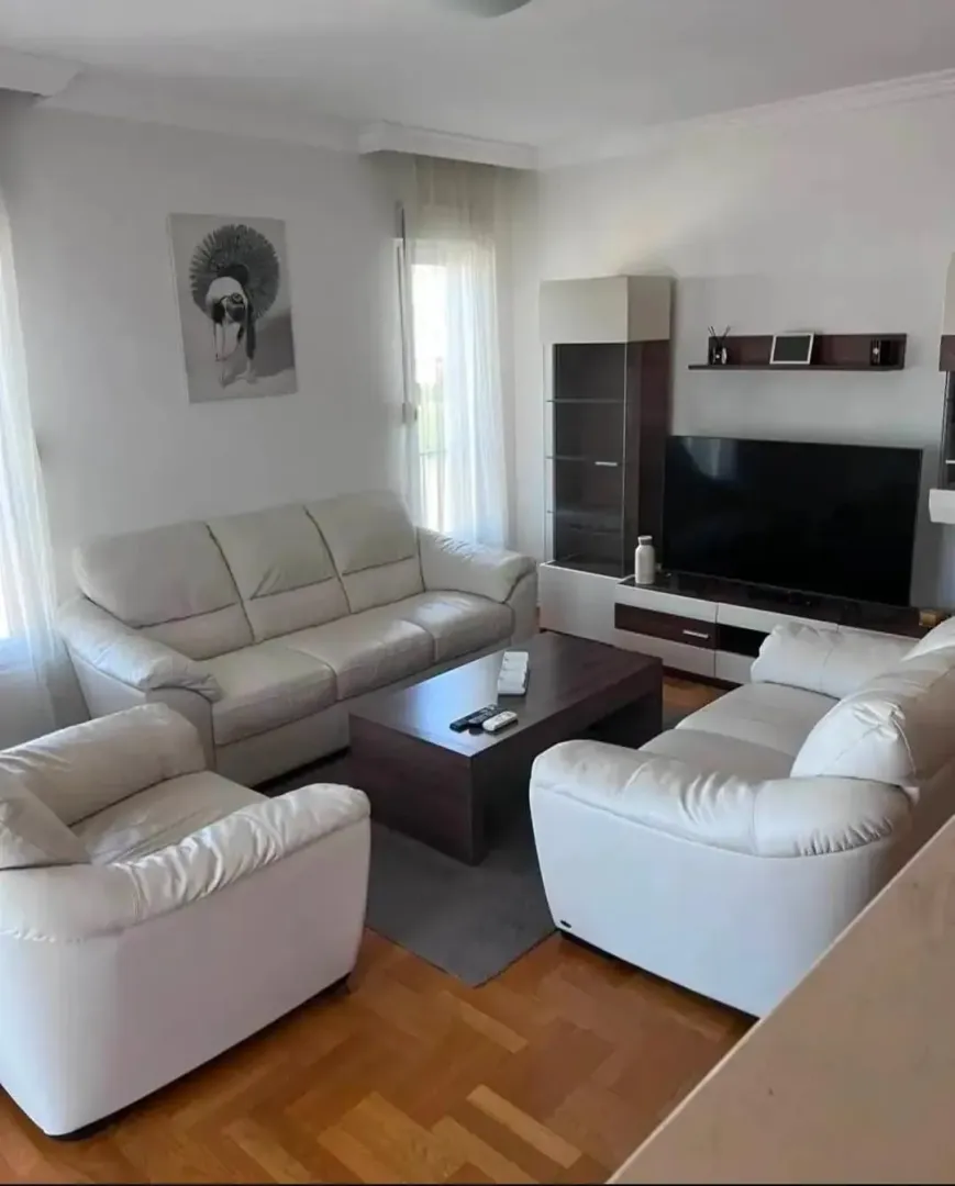 Svijetao i uredan dnevni boravak sa garniturom i televizorom.
