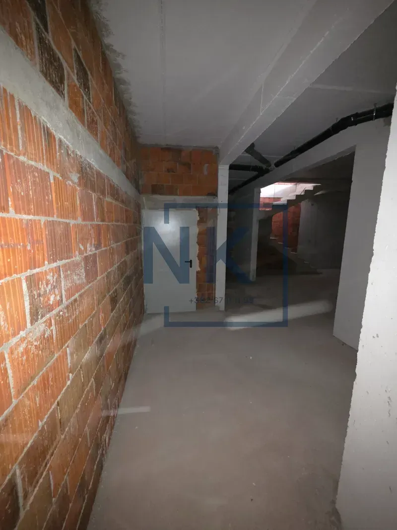 Interior of a property under construction with concrete floors and brick walls.