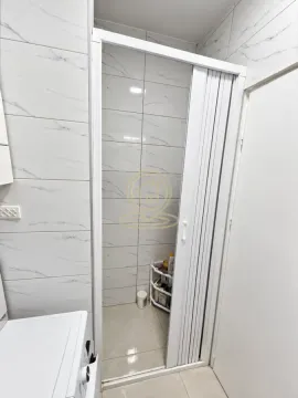 Pogled na kupatilo sa belim pločicama i harmonika vratima. - image 11