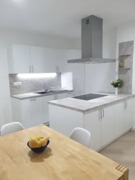 Moderna bela kuhinja sa ostrvom i trpezarijskim stolom u prvom planu. - image 2