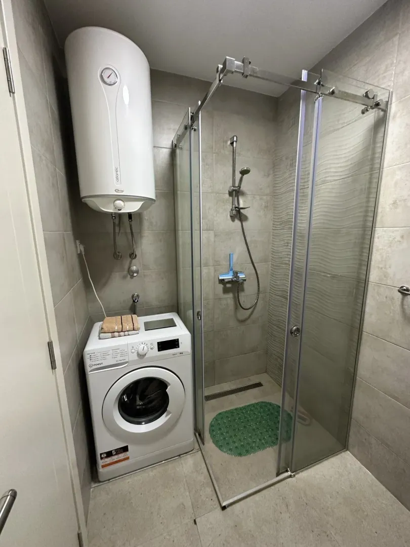 Bright bathroom with a shower cabin and a washing machine.
