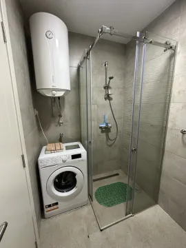 Bright bathroom with a shower cabin and a washing machine. - image 11