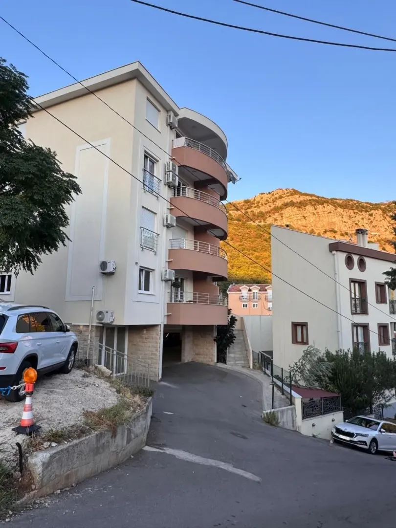 Spoljašnji izgled stambene zgrade sa terasama i prilazom.