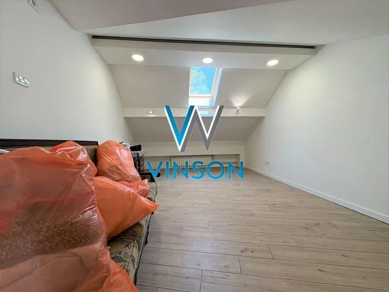 Attic space with wooden flooring and a roof window.