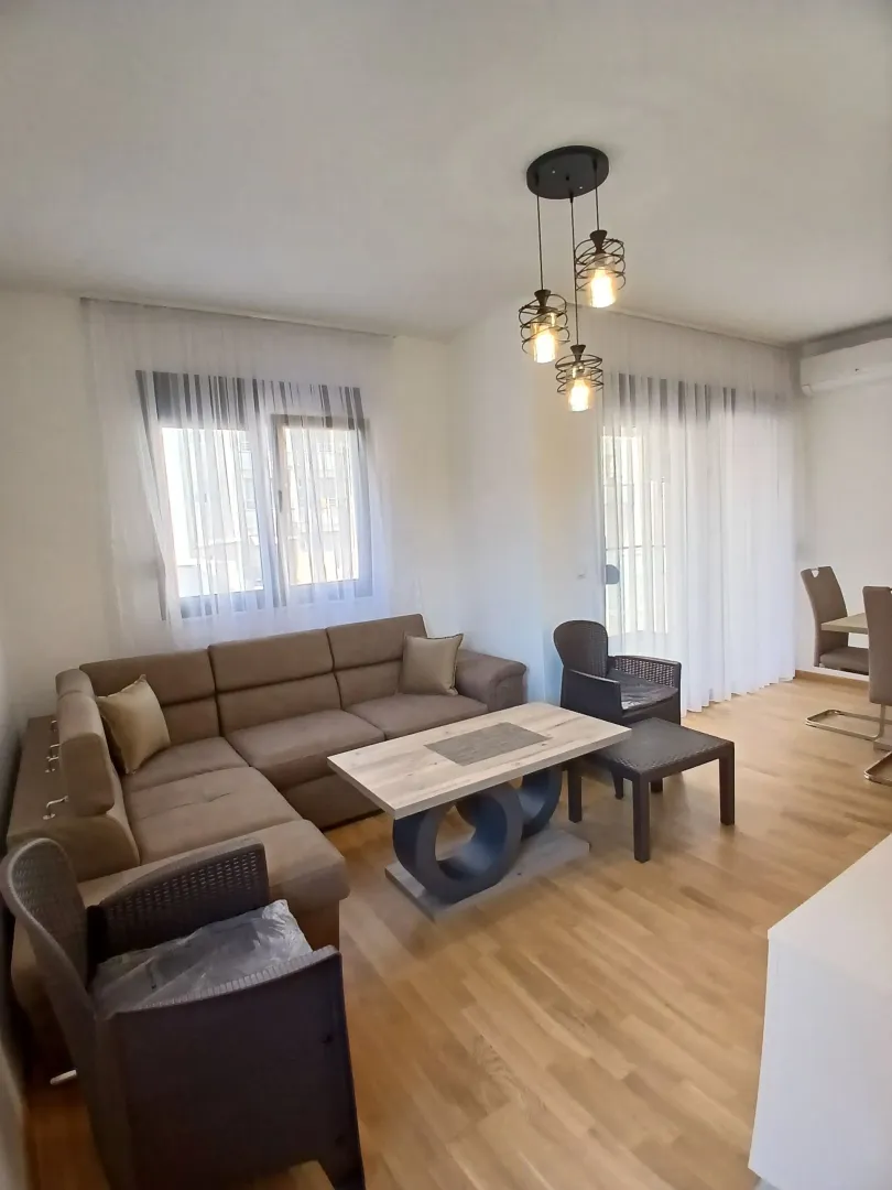 Prostrana dnevna soba sa ugaonom garniturom, stočićem i modernim osvjetljenjem.