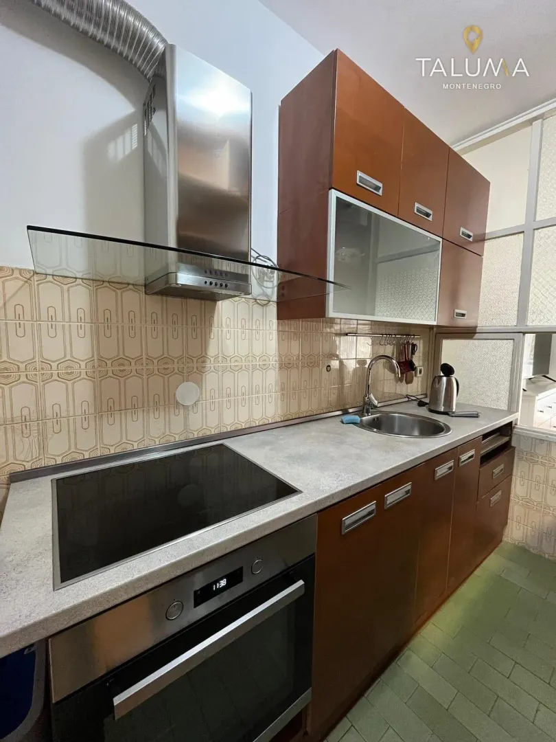 Kitchen with wooden cabinets, built-in oven, hob, and a sink.