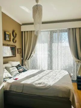 Nameštena spavaća soba sa bračnim krevetom, lusterom i prozorom sa zavesama. - image 8