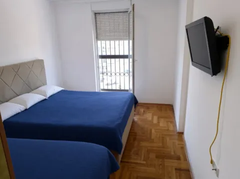 Spavaća soba sa bračnim krevetom, parketom i televizorom na zidu. - image 7